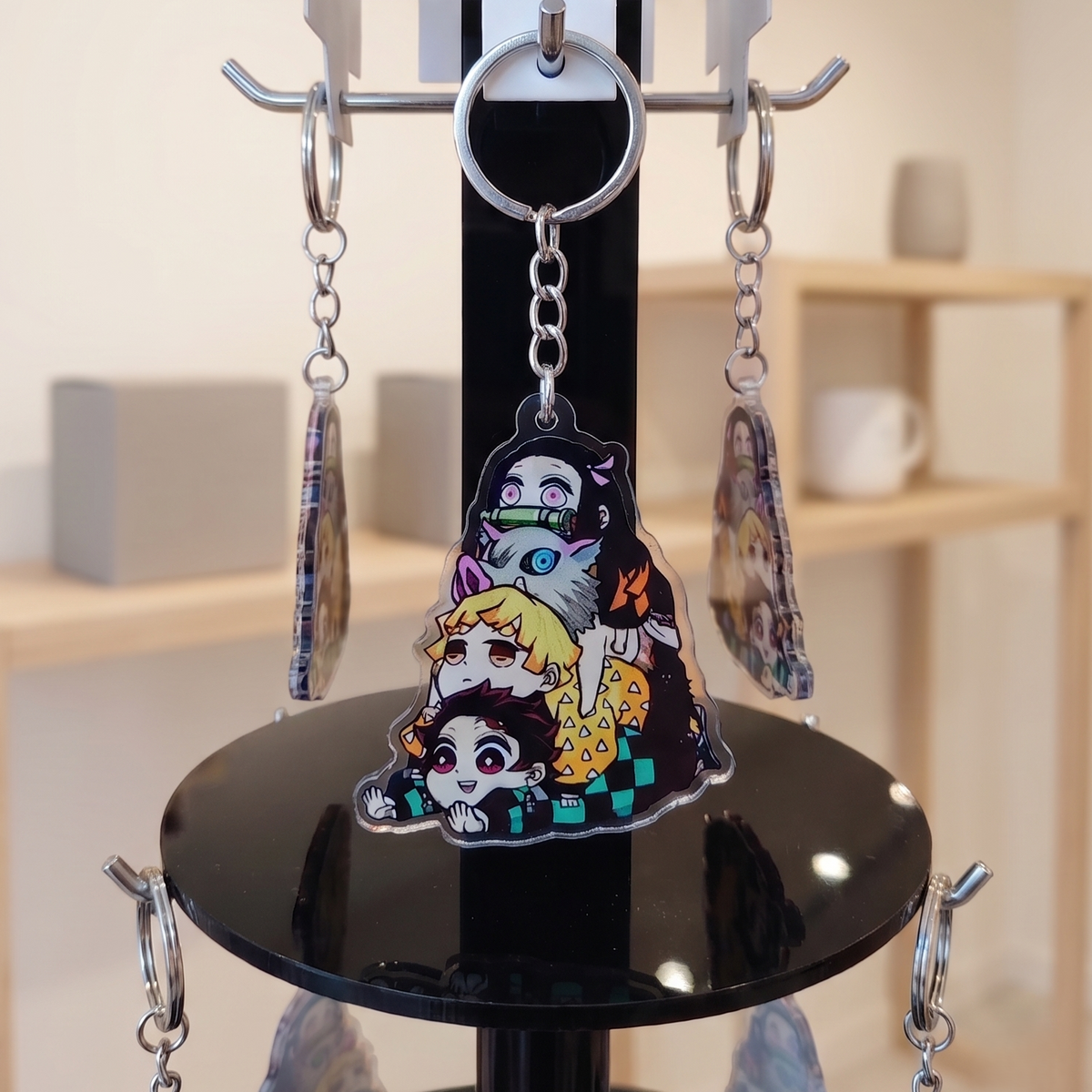 Demon Slayer anime merchandise acrylic keychain hanging on a black retail display stand