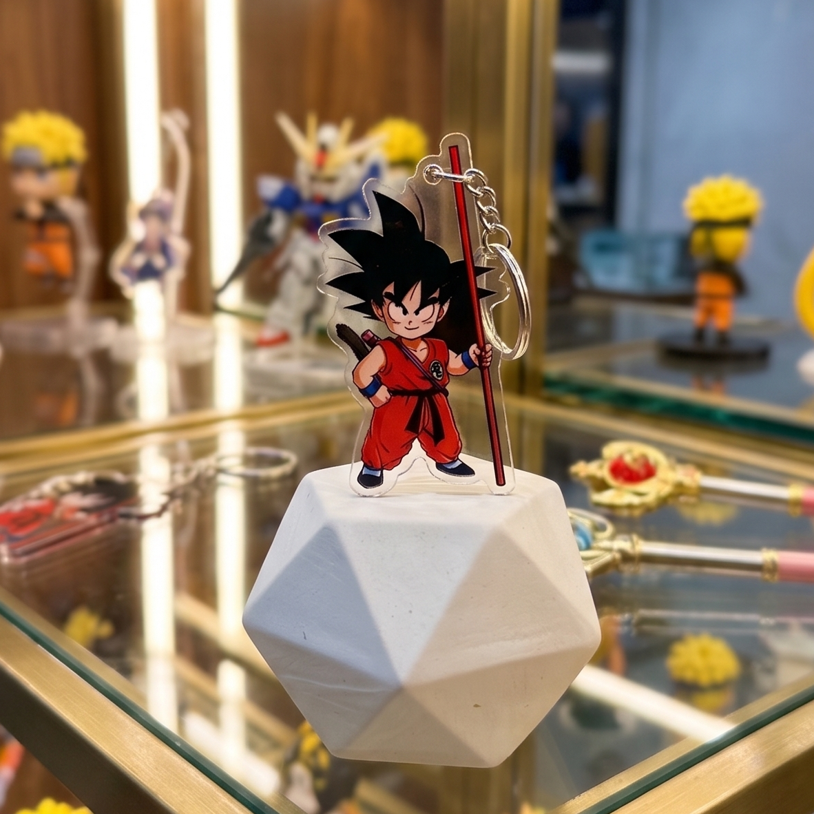 Kid Goku Dragon Ball anime acrylic keychain displayed on a white geometric stand inside a glass collector cabinet