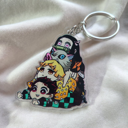 Clear acrylic Demon Slayer Kimetsu no Yaiba group character keychain lying flat on soft white fabric