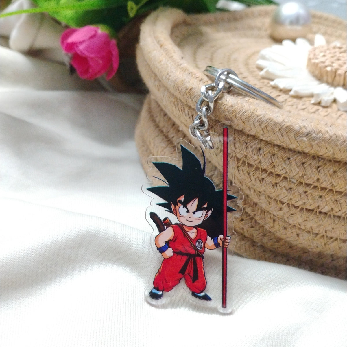 Dragon Ball Kid Goku anime keychain resting against a woven straw coaster with a floral background